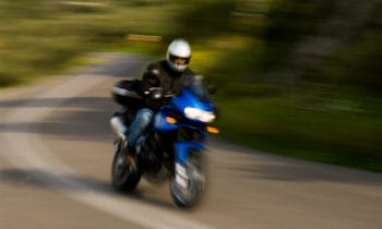 A person riding a motorcycle down a curvy road using motorcycle chocks.