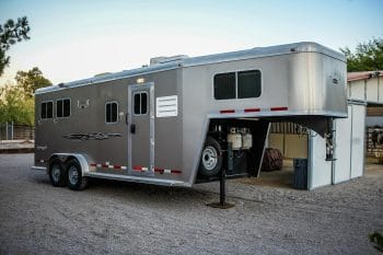 A rented silver horse trailer parked in a gravel lot.