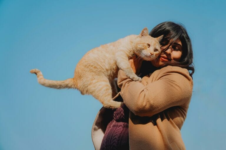 A pregnant woman comfortably carrying a cat.