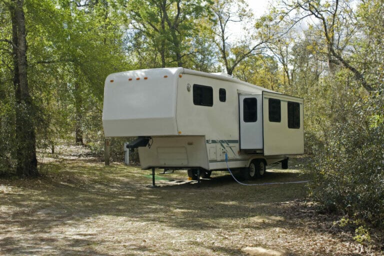 A camper parked in a wooded area.