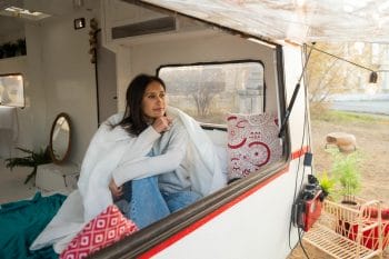 A woman gazes out the window of a camper van, contemplating her next adventure on the road with her RV.